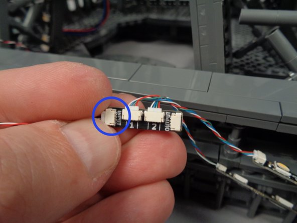 Take another light strip pair with connected adapter board and, as shown by the blue circle in the photo for this step, connect the end of the control cable coming from the second adapter board to the INPUT plug on the third adapter board.