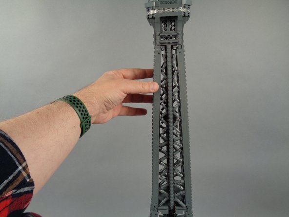 As shown in the photos for this step, re-attach the top rear tower frame section.