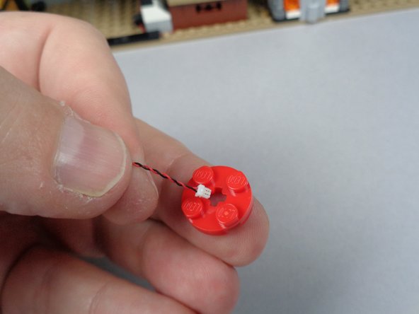 As shown in the second and third photos for this step, feed the plug for the LED light through the hole in the center of the jar base and pull the wire through so the LED light sits flat on the top of the plate.