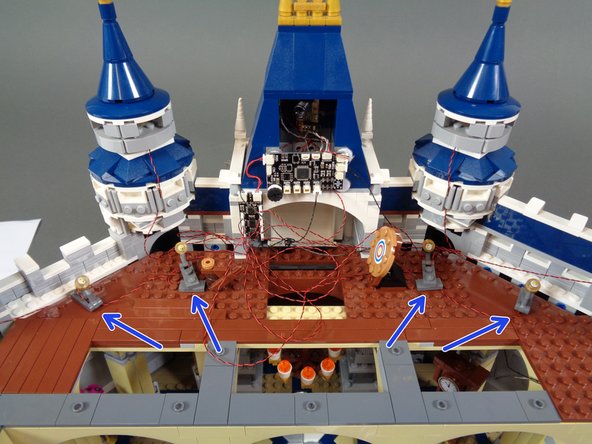 After mounting and connecting the four warm white spotlights, they should be distributed along the back of the castle wall approximately like the lights in the photo (see the blue arrows).