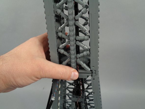 As shown in the photos for this step, re-attach the top rear tower frame section.