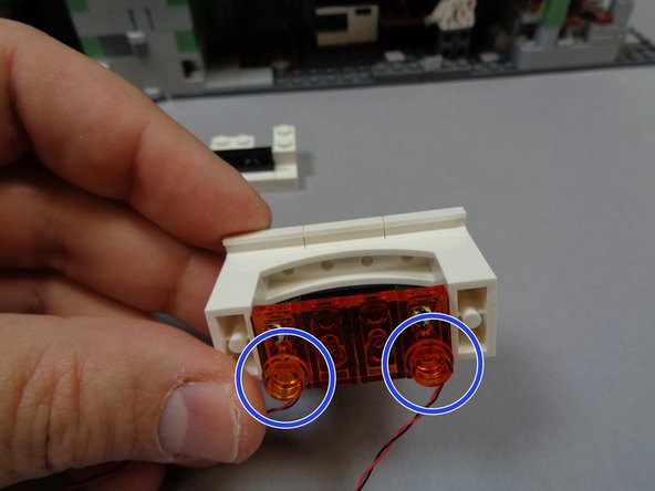 As shown in the second photo, attach the 1x2 transparent orange LEGO® plates with the orange lights to the bottom of the fireplace on either side.