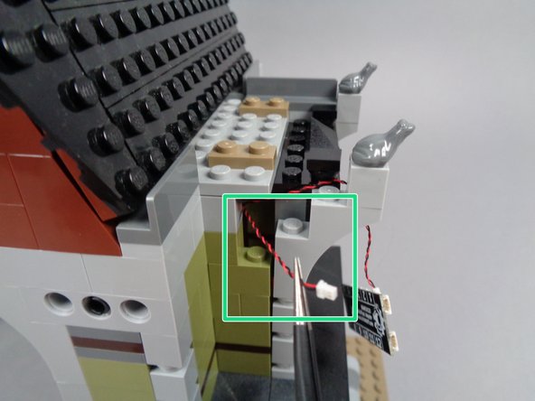 As shown by the green square in the first photo, pull the front porch light wire out through the same gap in the front wall as you used for the fireplace light wire.