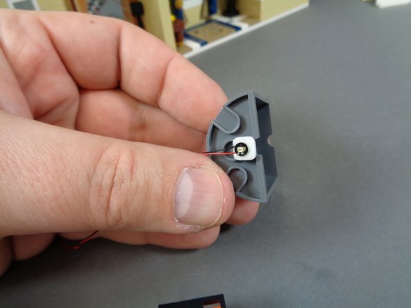 As shown in the first photo for this step, attach the orange Pico LED light to the bottom of the dark bluish gray half-cylinder toward the front (the straight edge of the half-cylinder).