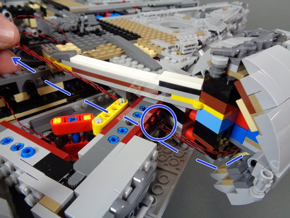 As shown by the blue dotted lines and circle in the third photo, feed the four cockpit control panel wires through a hole in the Technic brick in the Falcon frame, and into the open space near the &quot;engines&quot; speaker.