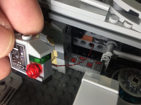 Place the transparent red round LEGO plate on top of the Pico LED, feed the LED light wire under the center section of the Falcon, then re-attach the panel as shown in the third photo.