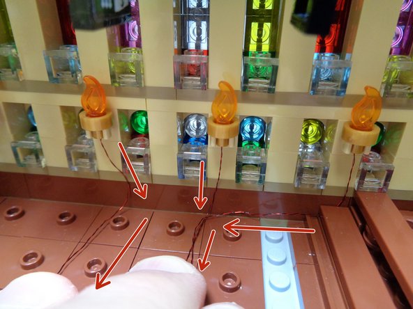 As shown in the second photo, run the wire from the first torch near the second torch, then run the wires from the first three torches toward the outer edge of the hall as shown by the red arrows in the second photo.