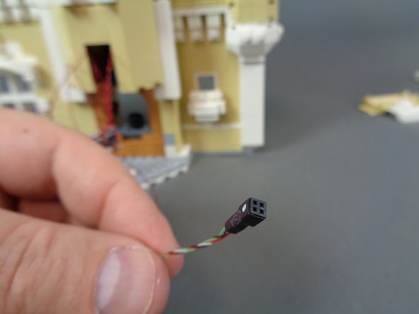 As shown by the photos in this step, take the end of the wire with the black &quot;female&quot; connector (without gold pins) and feed it up through the spinning room and through the top of the top open section as shown in the third photo.