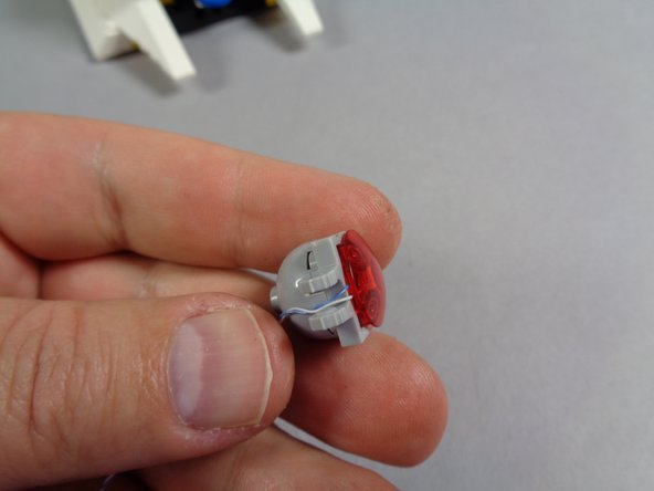 As shown in the first photo for this step, make sure the LED light wire passes between the two parts of the clip.