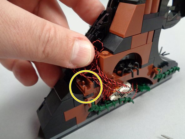 As shown by the yellow circle in the second photo for this step, re-attach the hinge base and finish coiling up excess wire.
