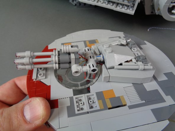 As shown in the second and third photos, you should now have the laser cannon re-attached to the main mount with the light wires passing through the two outer Technic holes in the mount.