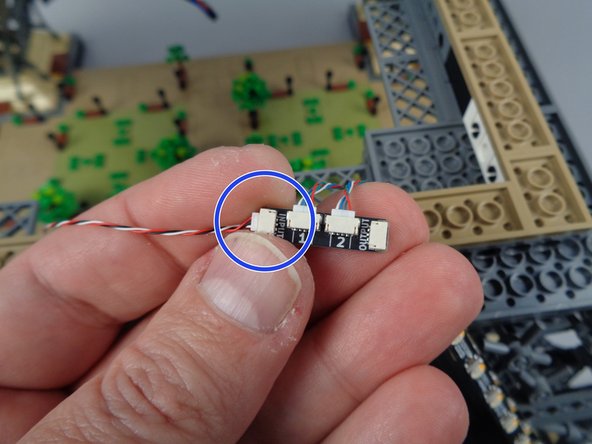 As shown in the first photo for this step, carefully reach under the center of your tower to find the loose control cable coming from the second adapter board and second set of light strips.