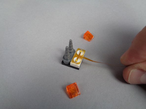 As shown in the first photo for this step, remove the 2-light flickering flame assembly from one of the bags inside of BOX #2.  The assembly is flexible and fragile, so handle it carefully.