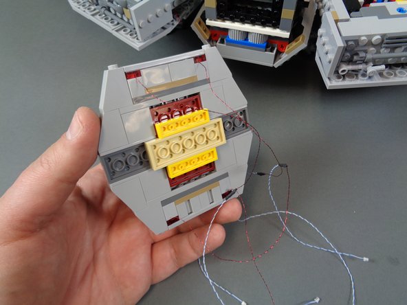 As shown in the first photo, mount the four pre-lit docking bay lights into the left-side docking bay cap.  See Step 43 if you need a refresher on how to mount the lights.