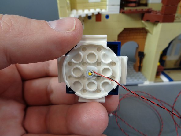 As shown in the photos for this step, remove the small tower top above the kitchen, and attach a warm white Pico LED light to the center using the sticky square you attached in the previous step.