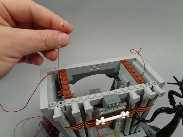 As shown in the third photo for this step, re-attach the reddish brown 1x6 plate, holding the banner light wire in place.