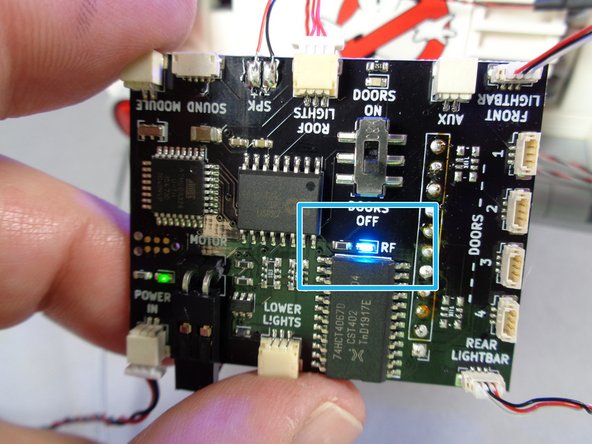 The red arrow in the first photo points to the red LED light on the transmitter.  Whenever you press a button on the remote, this light should turn on (it is off in the photo).
