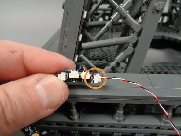 As shown by the orange circle in the photo for this step, take a second control cable and connect it to the OUTPUT plug on the adapter board.