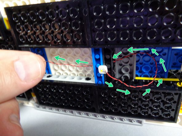 The green arrows in the first photo for this step show how you should pass the LED light wire through the center hole in the Technic bricks that support the roof.