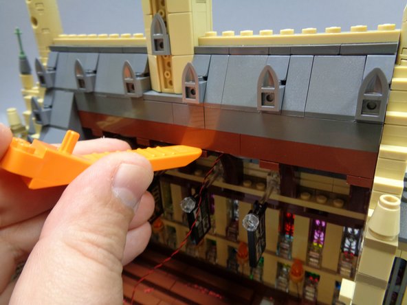 Using a LEGO brick separator, carefully separate the roof section from the brown roof braces.  This will allow you to run the light wires between the roof and the roof braces.