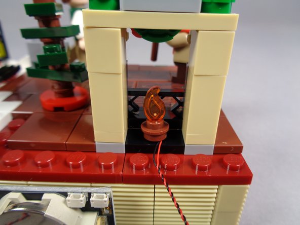 Take the small flame with the tip clipped off from the bag labeled &quot;Core Parts&quot; and press it into the top of the round brown plate as shown in the second and third photos.