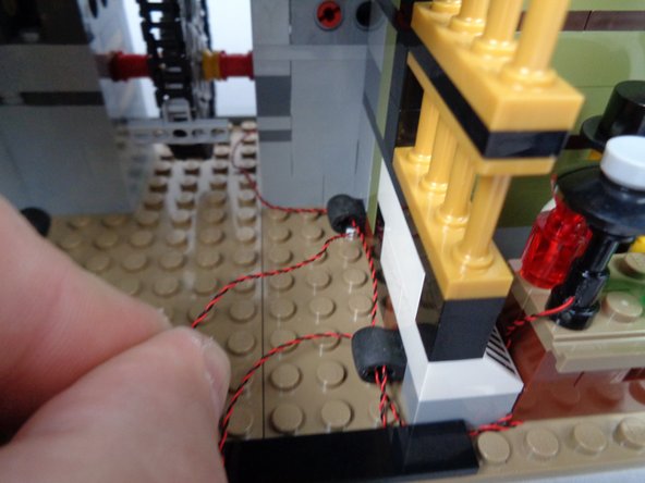 As shown in the photos for this step, continue routing the lamp LED light wire back through the rear of the elevator shaft and toward the BRANCH06X adapter board.