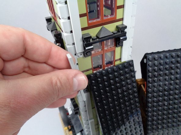 As shown in the photos for this step, re-attach the long LEGO tiles on three sides of the tower to secure it.