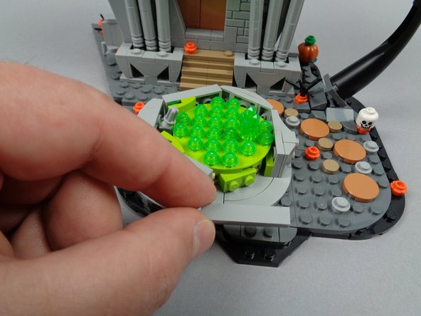 As shown in the second photo for this step, remove the front side piece from the fountain base.