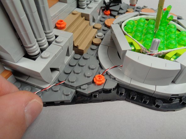 As shown in the second photo for this step, re-attach the plate on top of the wire to hold it in place.