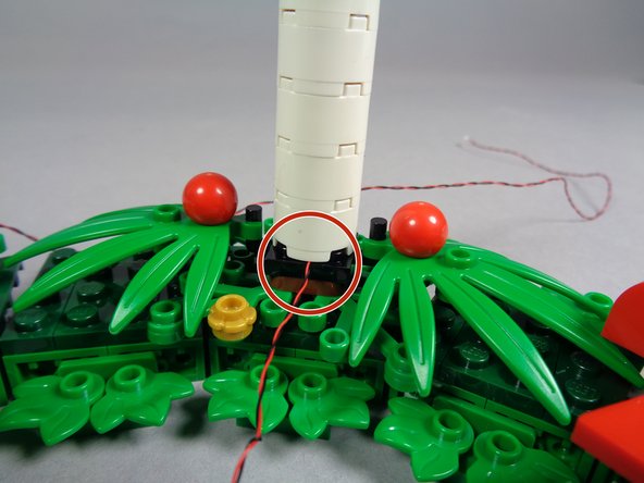 As shown by the red circle in the second photo, when you re-attach the two candles with the long wires, make sure the wire for each candle extends toward the inner side of the wreath, and make sure the wire runs between, not on top of, studs.