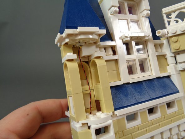 As shown in the photos for this step, re-assemble the turret next to the bedroom, making sure the LED light wire passes all the way down into the interior of the magic room.