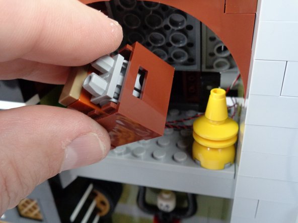 As shown in the first photo for this step, replace the large brown storage box in the attic, being careful that all wires run behind the storage box.