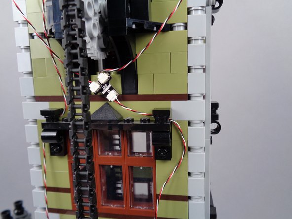 Continue routing the light strip wire downward as shown in the photos for this step, looping the wire through window frame parts as you go.