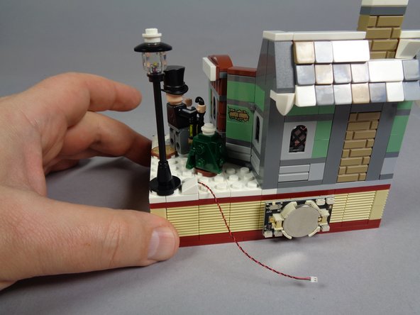 As shown in the second photo, re-attach the lamp post to the base with the wire for the LED light passing toward the battery pack.