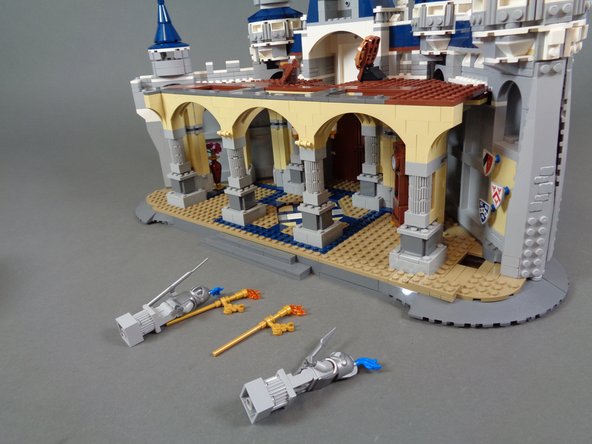 To prepare, carefully remove the top two sections of your castle as shown by the blue and red arrows in the first photo.