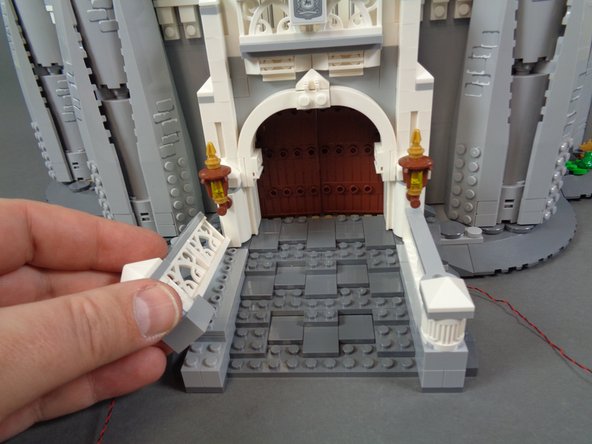 As shown in the photos for this step, re-attach the white railings on either side of the front steps.