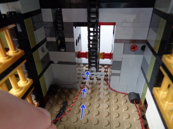 As shown by the green arrows in the second photo, pass the wire through the center of the back rubber Technic part.