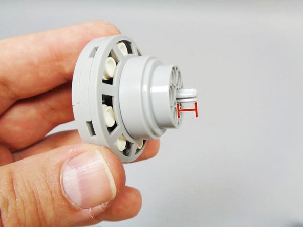 After fully inserting the axle, the end should stick out just a little (as shown in the third photo).  It is important that it stick out just enough to catch on the parts below, but not too far that it extends into the top of the first transparent core brick (or the top LED will be damaged).