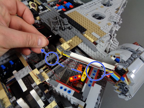 Route the light wire as shown by the dotted blue lines in the second photo.  The two blue circles show where the wire should pass through stud holes in the Falcon frame bricks.