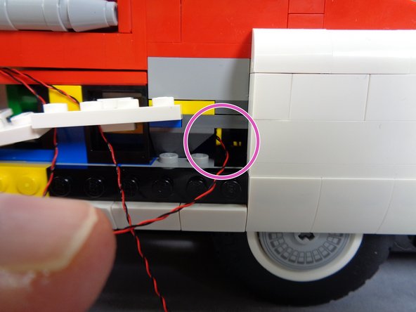 As shown by the purple circle in the second photo, pass both wires through the side of the car's frame and into the inside rear.