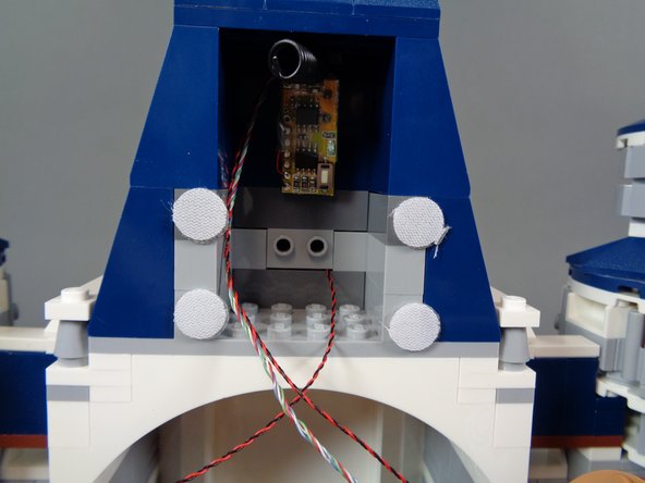 Remove the TRUNK08 master controller board from the box labeled &quot;Main Control Board and Spotlights,&quot; and mount the board to the four Velcro dots as shown in the third photo.  Attaching the board with the Velcro dots will make it possible to remove and re-attach the board later if needed.