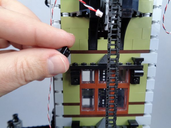 As shown in the photos for this step, remove the top left plate and tile from the topmost window frame on the back side of the tower, and begin feeding the magnet switch wire downward.
