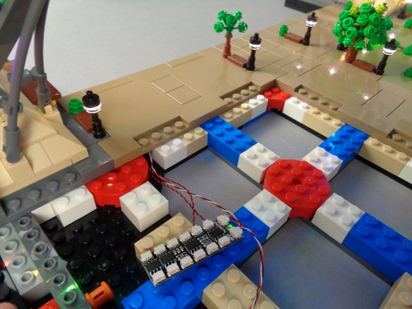 While preparing to re-attach the panel, make sure the wires for the two lamp posts pass through the gaps between the bricks under the panel, as shown by the yellow circle in the first photo.