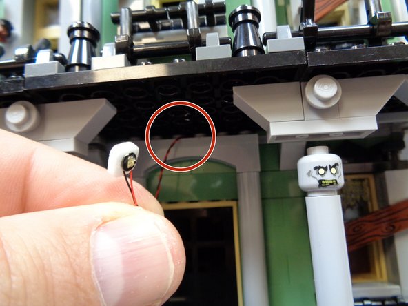 As shown by the red circle in the first photo, feed the wire from the yellow Pico LED light through the gap above the front door so the wire passes inside the house.