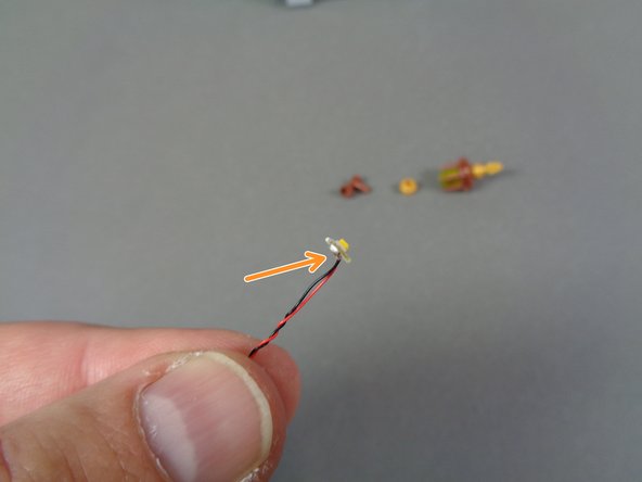 As shown by the orange arrow in the second photo, carefully bend two LED lights at the end of their wires, so the round white portion (with the light) faces forward.