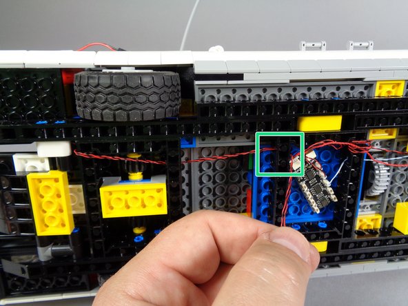 As shown by the green rectangle in the first photo for this step, pass the two tail light wires through the black Technic frame so the wires pass into the same space as the BRANCH09X adapter.