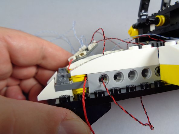 The second photo in this step shows how the red wire should pass-- between studs, not pinched.