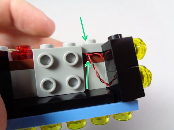 As shown by the orange rectangle in the second photo, carefully re-attach the gray bracket so the wires pass underneath.  The bracket should hold the wires, and the two black bricks, in place.