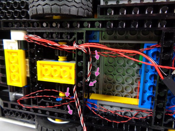 As shown by the red arrows in the first photo, the wires should be tight enough that none of them hang low enough to get caught in the wheel axle gears.