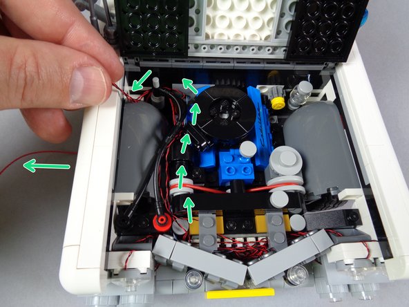 As shown by the green arrows in the first photo for this step, route the two strobe light wires along the same path as the red control wire: along the side of the engine, looped around the bar in the back, and down behind the wheel well.